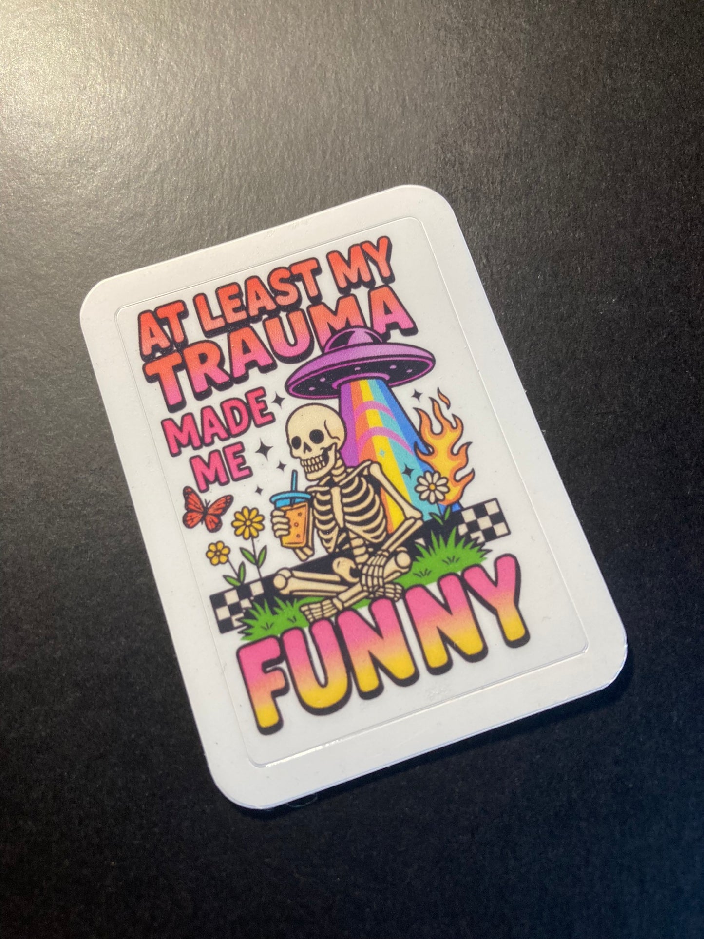 Colorful sticker with skeleton and text on a dark surface