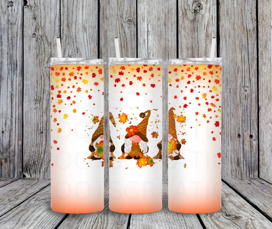 Tumbler  with autumn-themed design featuring gnomes and leaves on a wooden background.