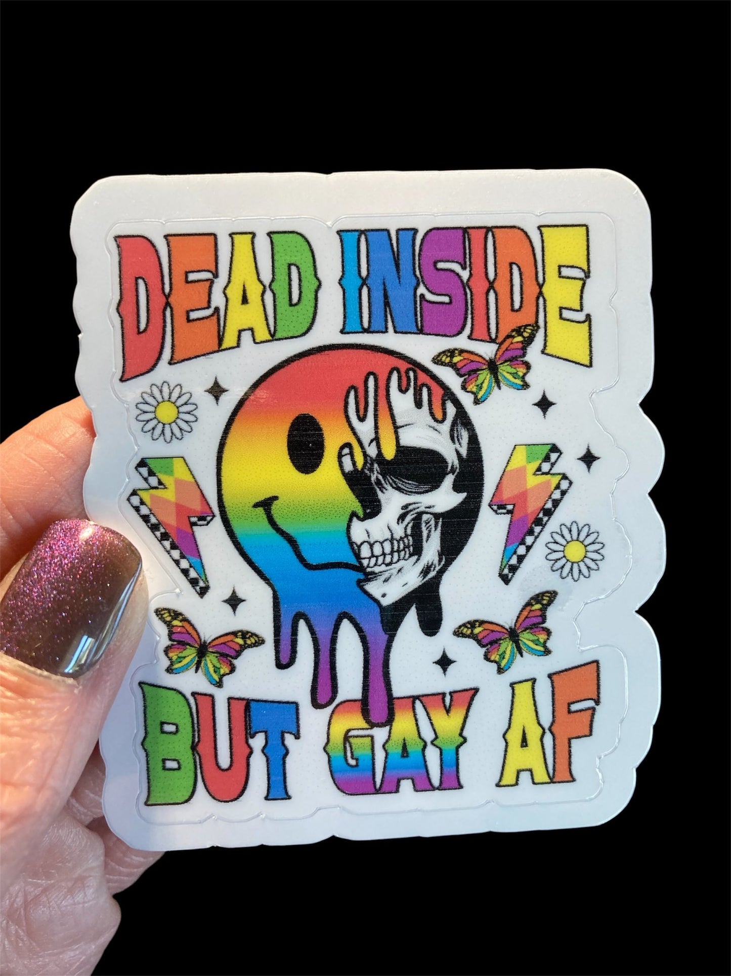 Sticker with colorful design and text held by a hand against a black background