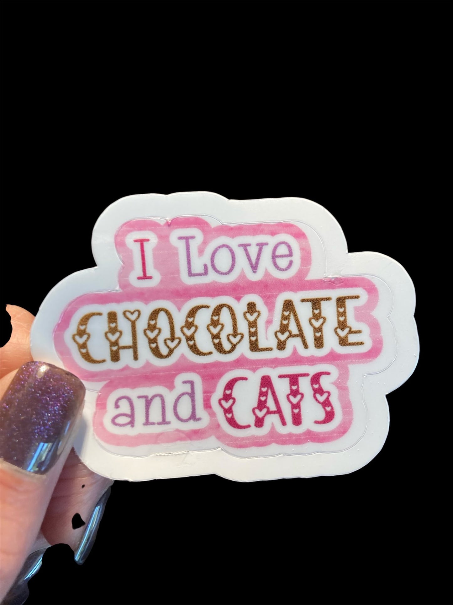 Sticker with 'I Love Chocolate and Cats' text held by a hand with glittery nail polish.