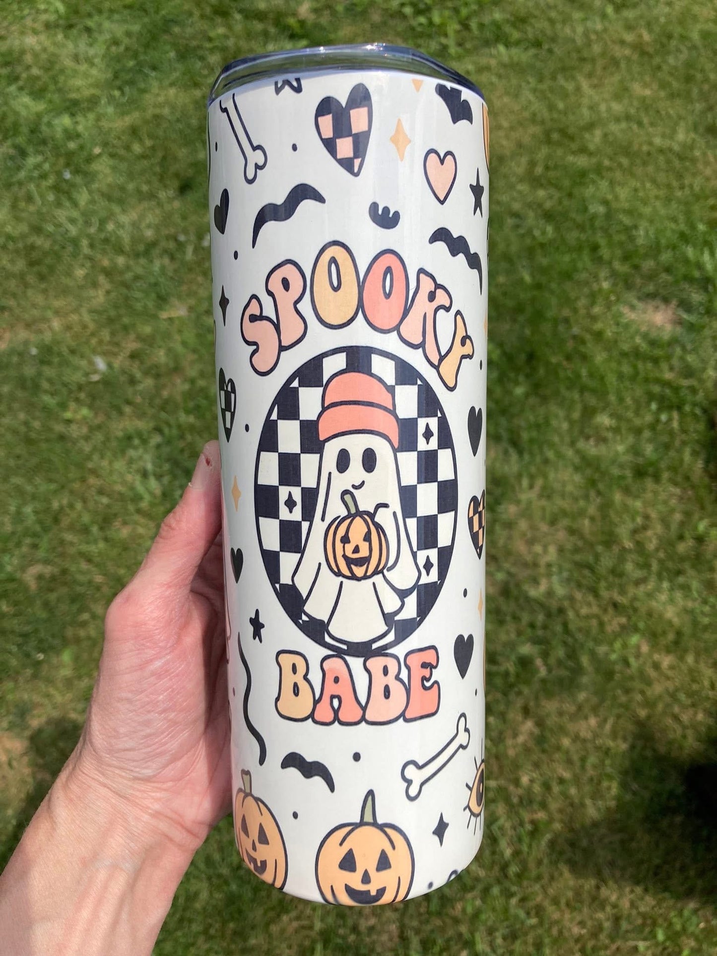 Spooky babe tumbler with cute ghost holding pumpkin surrounded by hearts, bats, and checkerboard pattern