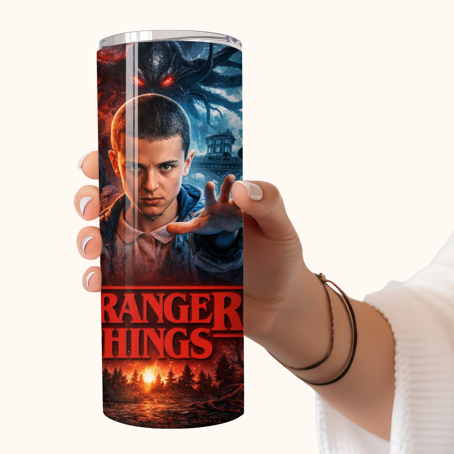 Hand holding a 20oz stainless steel tumbler featuring Stranger Things–inspired Eleven artwork with dark sci-fi and Upside Down themed design.