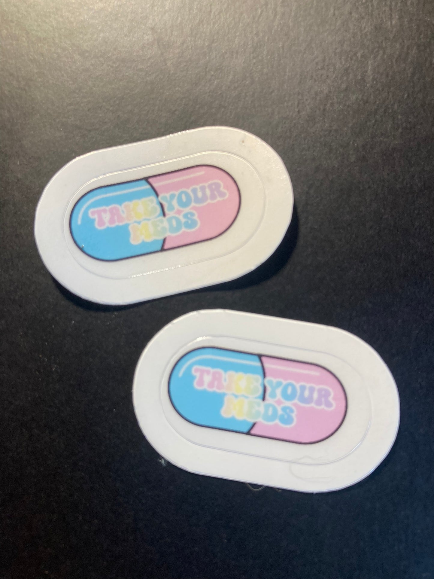 Two oval stickers with a blue and pink design on a black surface
