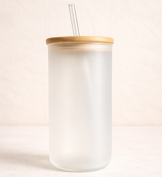 White tumbler with a wooden lid and straw on a light pink background