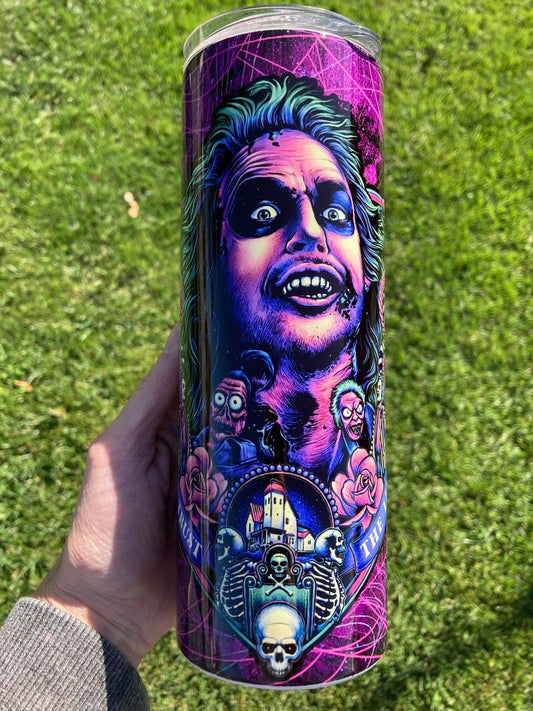 Pink and green Beetlejuice themed tumbler with “Never Trust the Living” design, spooky Halloween cup with straw.