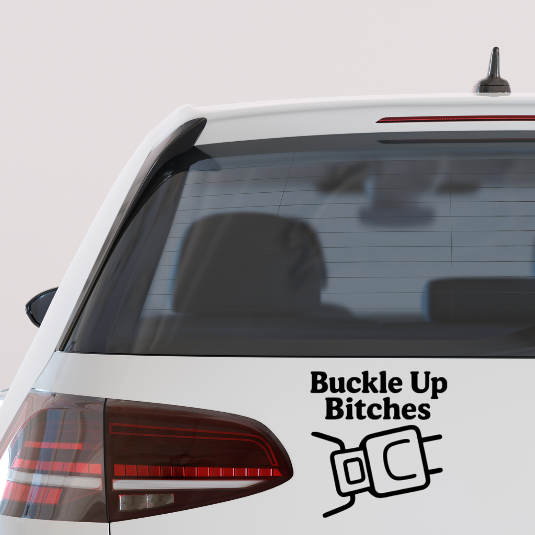 Black vinyl decal on a car window with the phrase “Buckle Up Bitches” and a seatbelt icon.