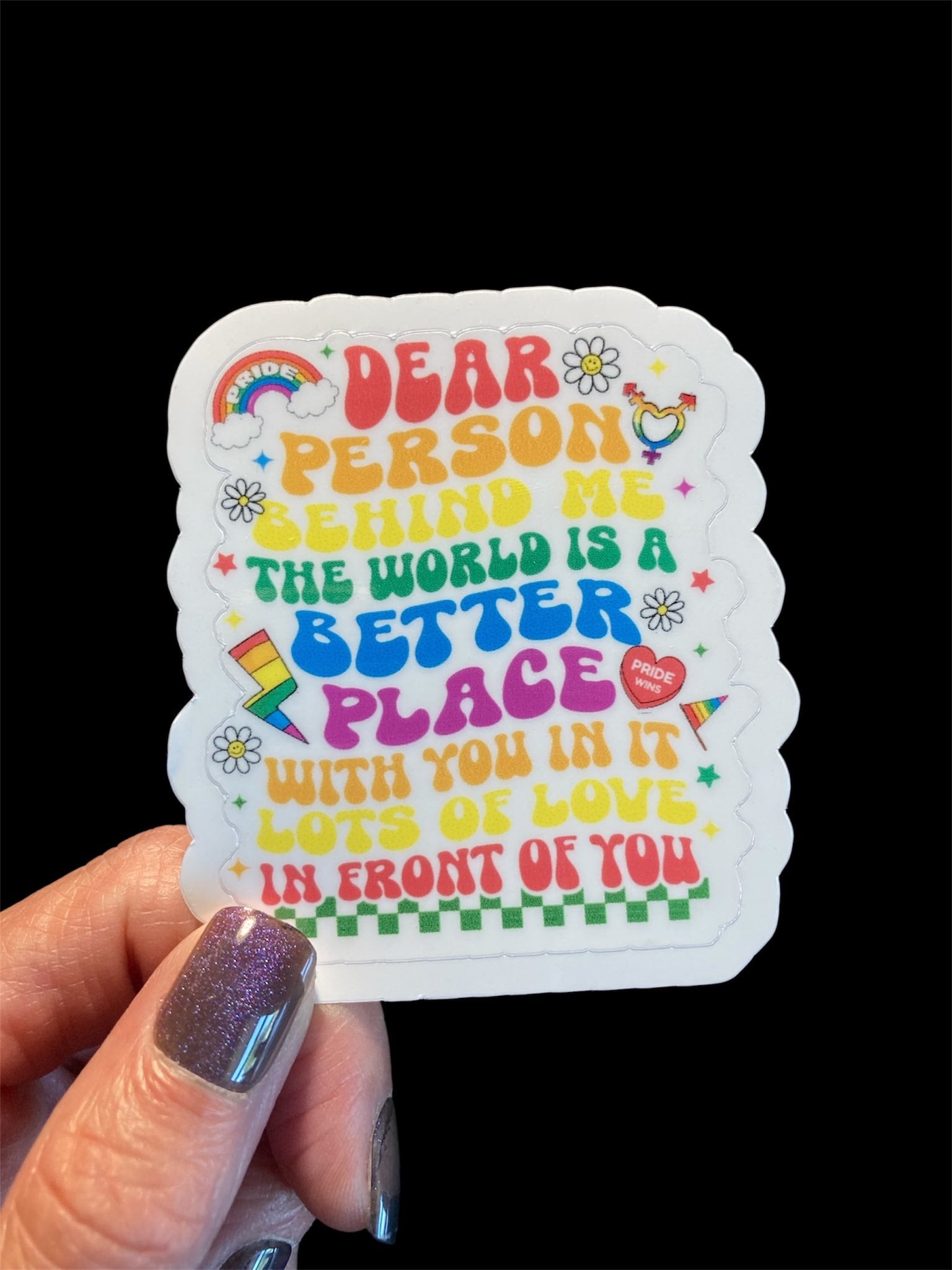 Colorful sticker with motivational message held by a hand against a black background