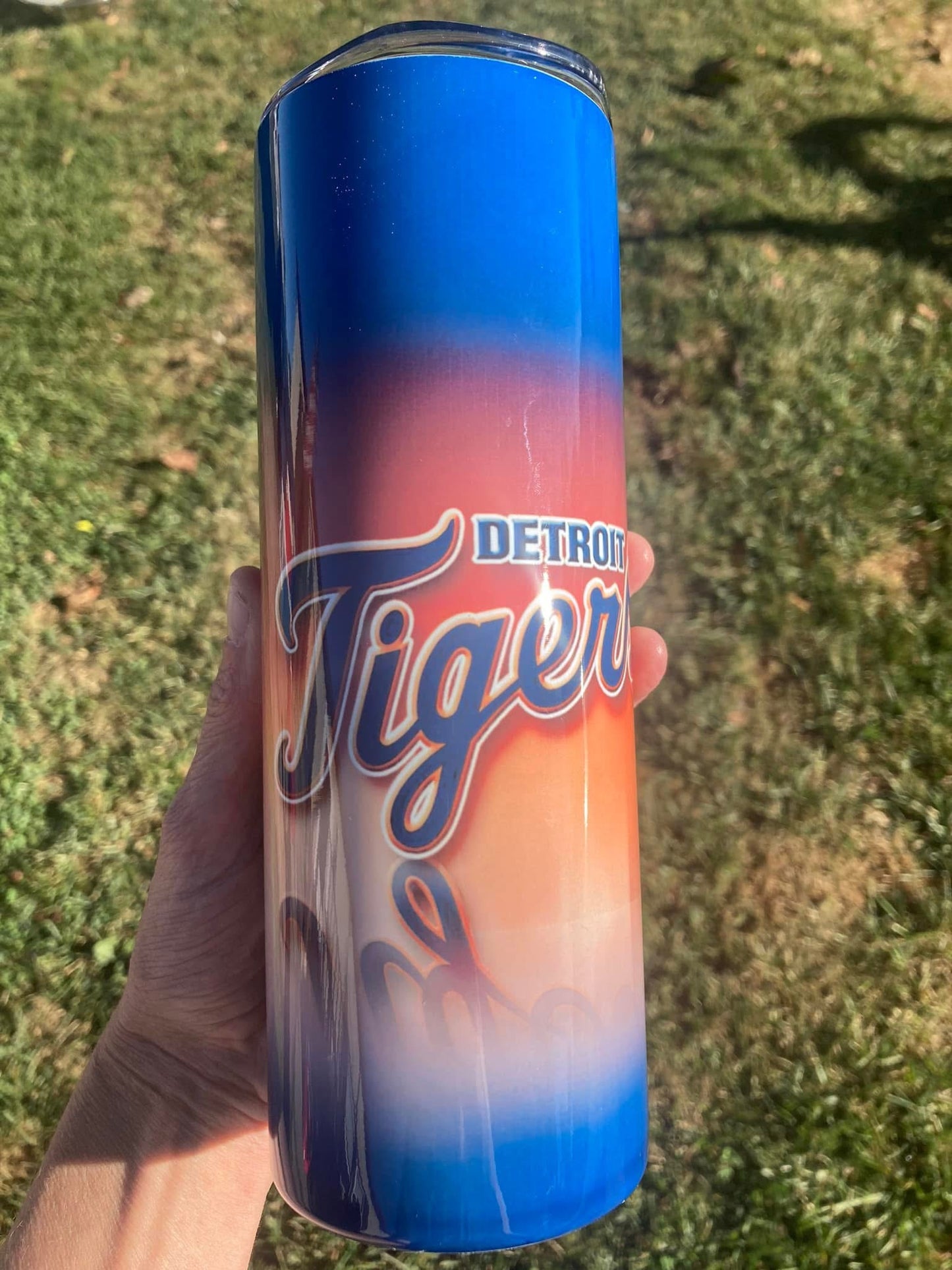 Can of Detroit Tiger Beer held in a hand with grass in the background