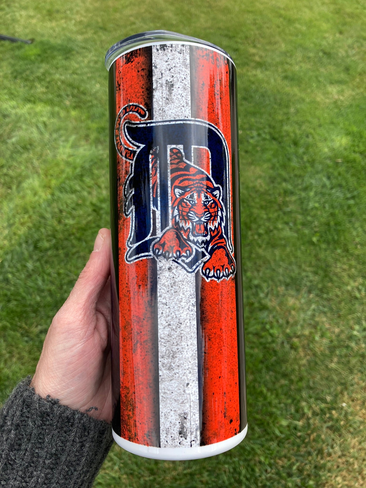 Tumbler with a tiger logo and 'D' on a grass background