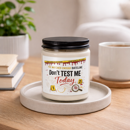 Candle with a humorous label on a wooden table with a plant and books in the background