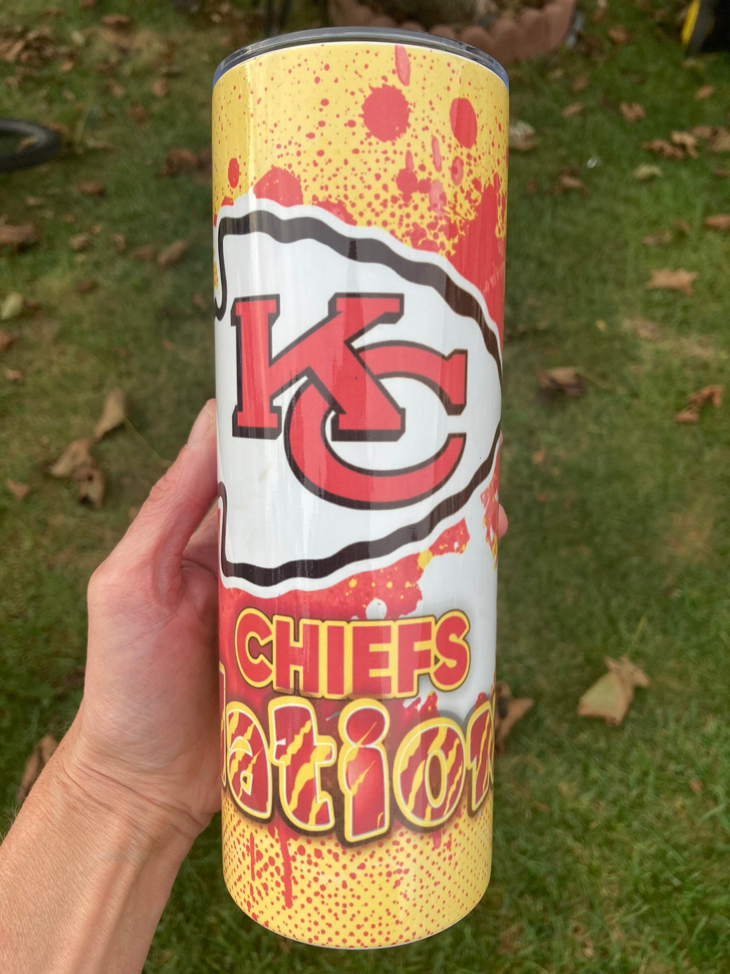 Tumbler with 'KC Chiefs Nation' design held by a hand on grass