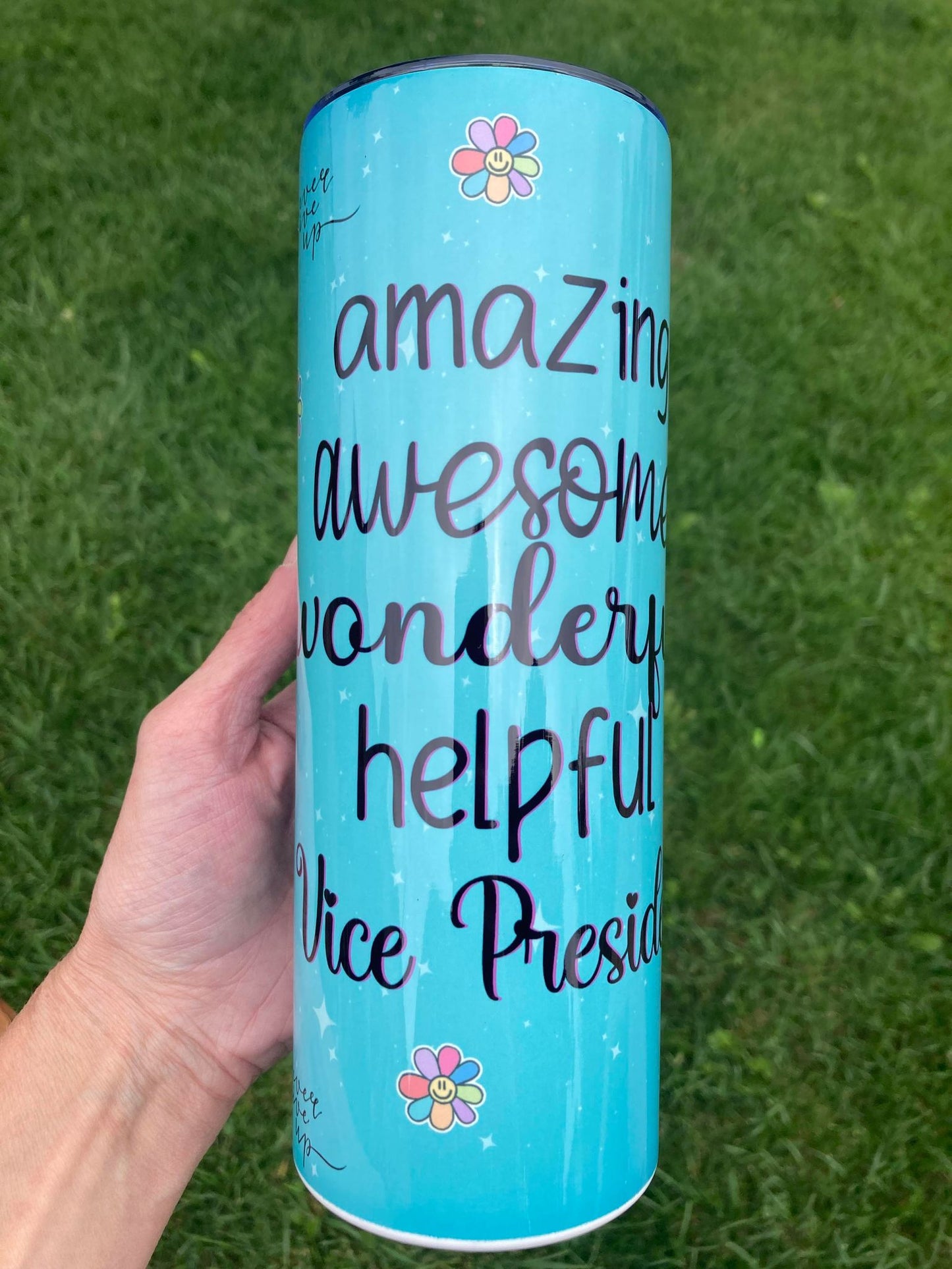 Blue cylindrical container with text and flowers on a grass background