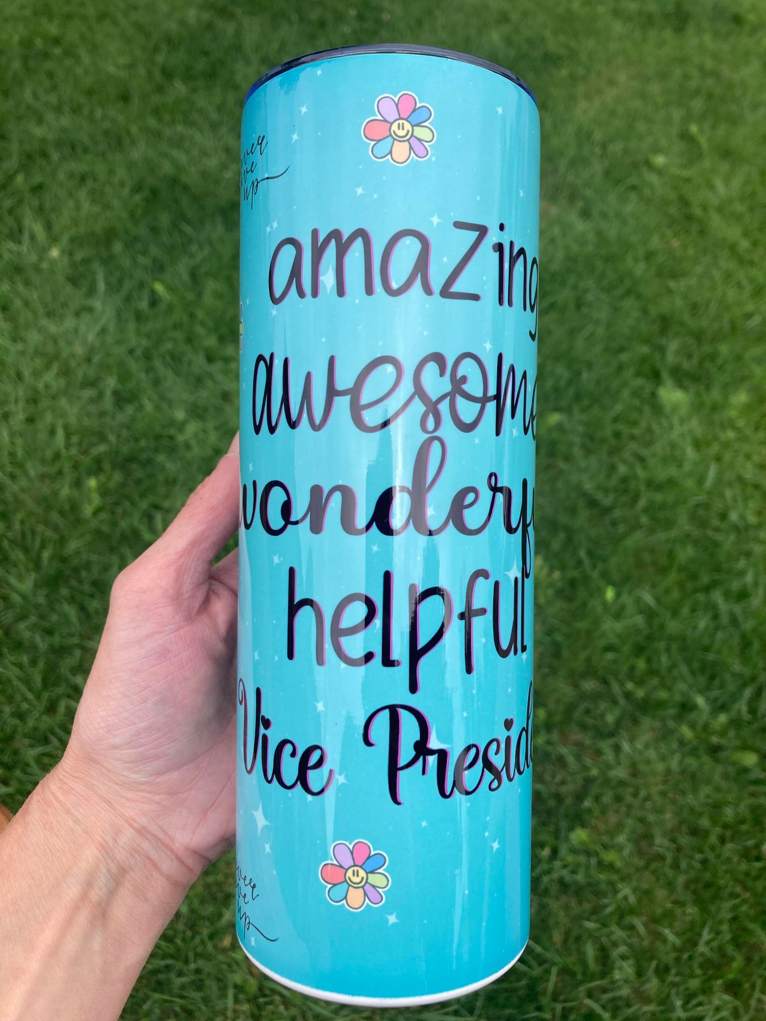 Blue cylindrical container with text and flowers on a grass background