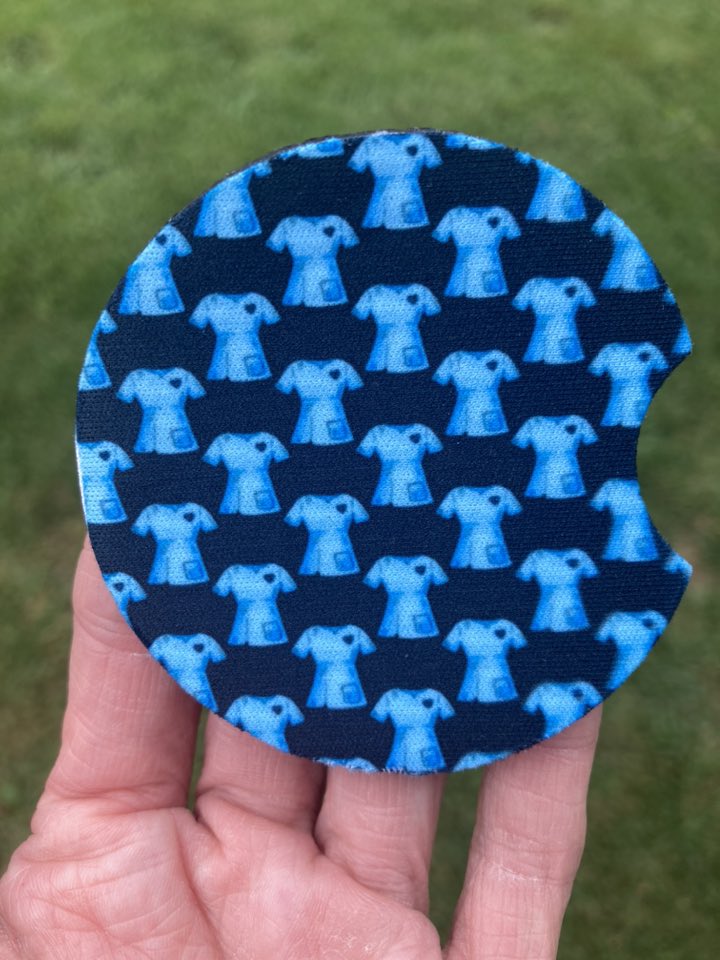 Circular fabric patch with blue medical scrub top pattern held in a hand against a grass background