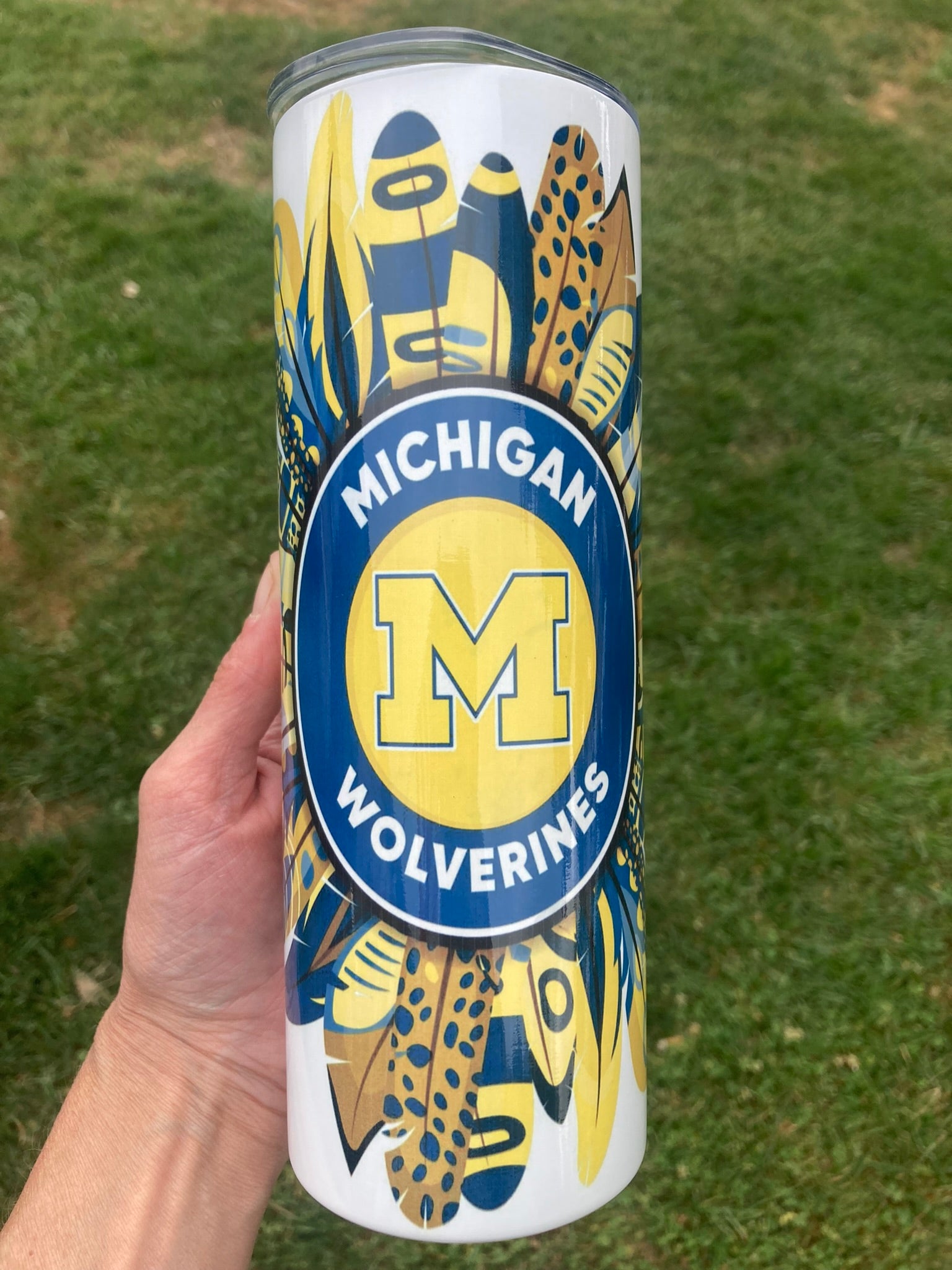 20oz Michigan Wolverines tumbler with blue and yellow feather burst design.