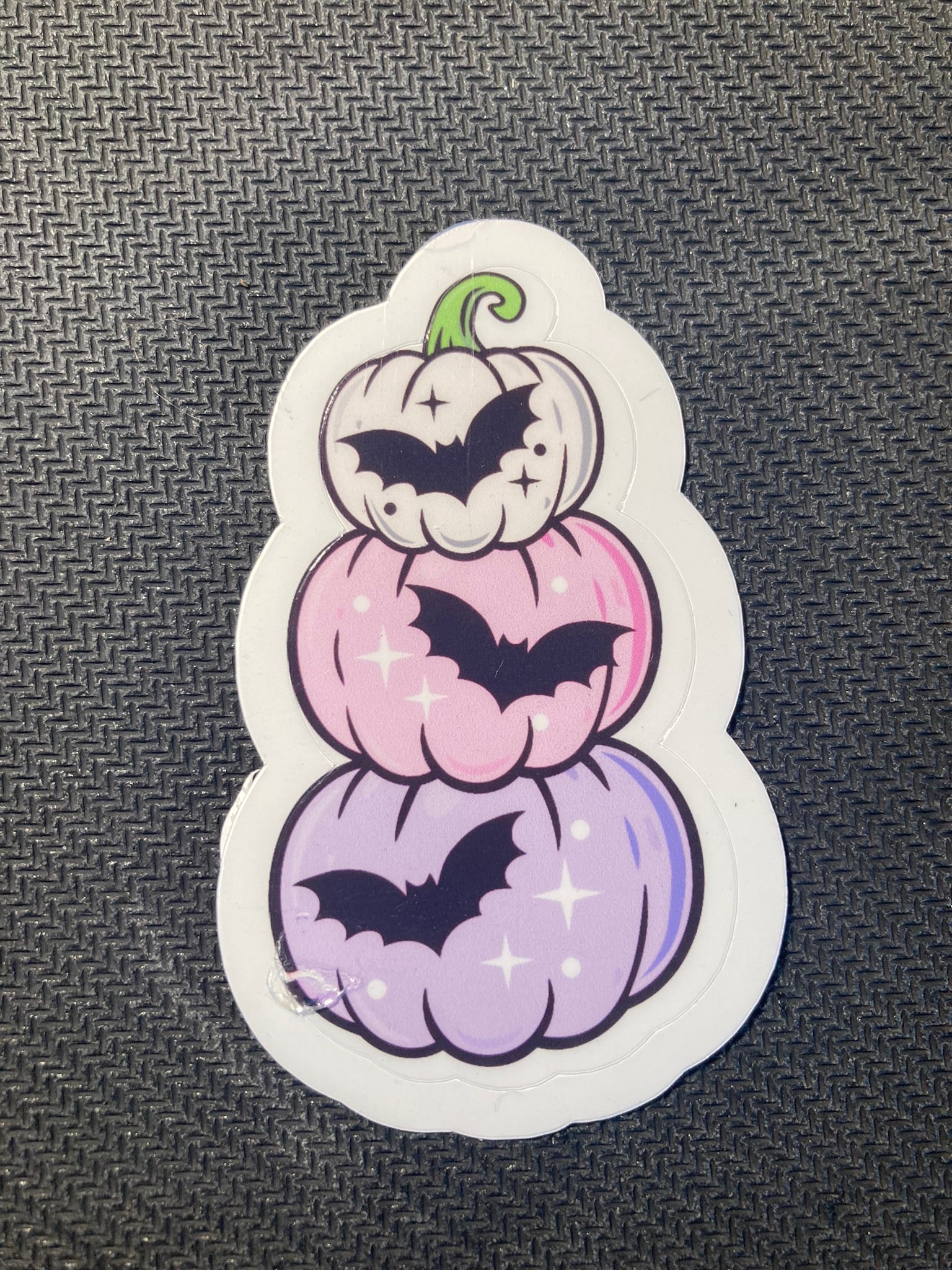 Halloween sticker with pastel purple and pink stacked pumpkins decorated with black bats and sparkles.