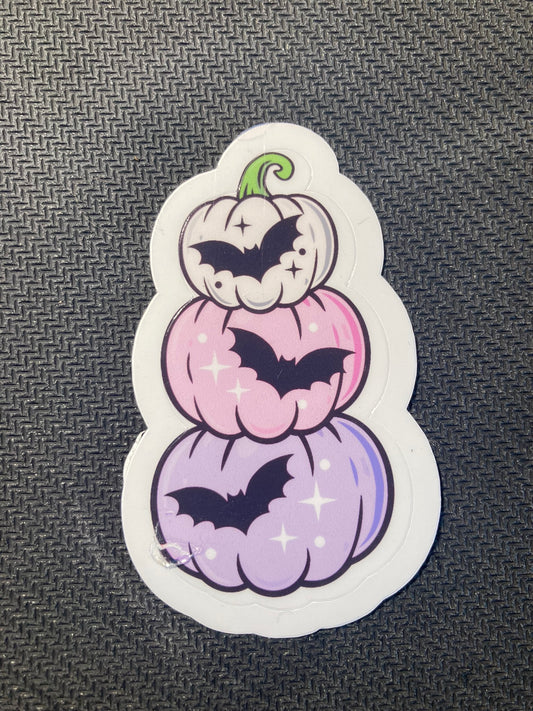 Halloween sticker with pastel purple and pink stacked pumpkins decorated with black bats and sparkles.