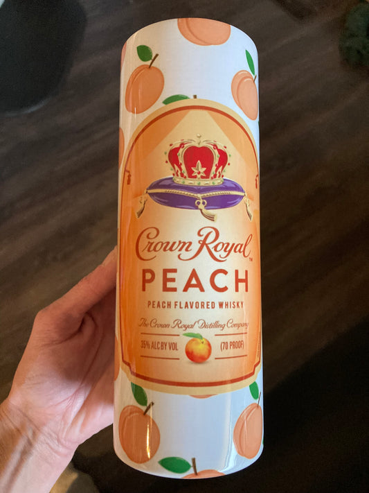 Crown Royal Peach whisky can held by a hand on a wooden surface