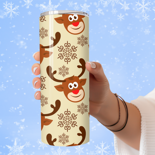 Tumbler with reindeer and snowflake design held by a hand against a snowy background