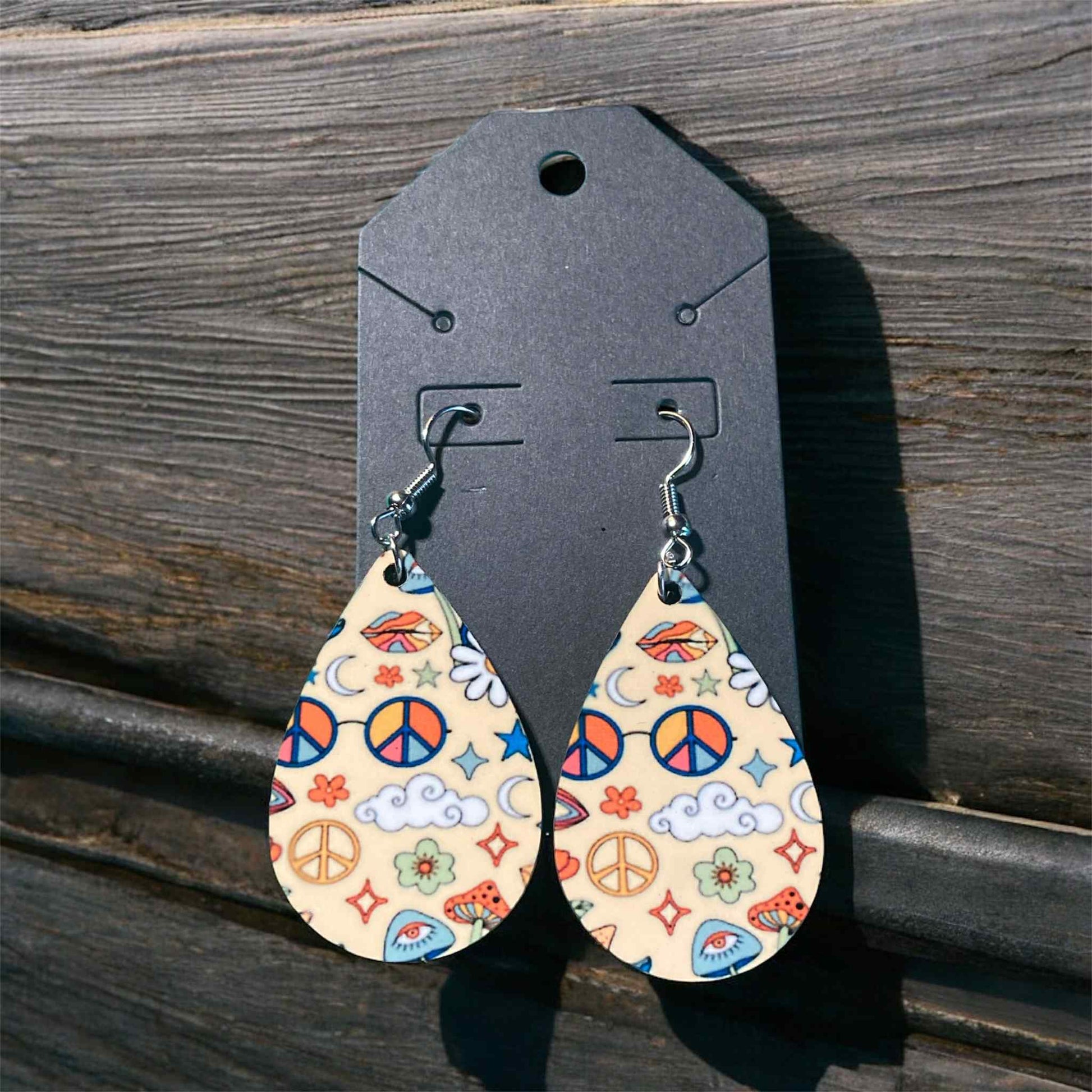 Teardrop earrings with retro peace signs, daisies, and colorful boho sublimation design