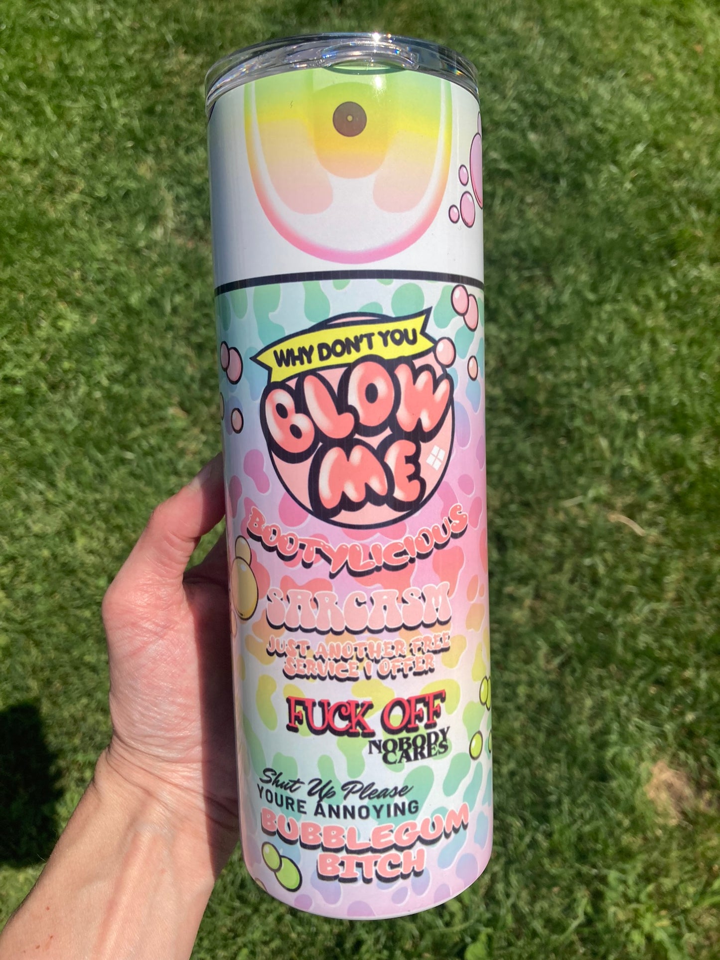 Cylindrical product with colorful design held against a grassy background