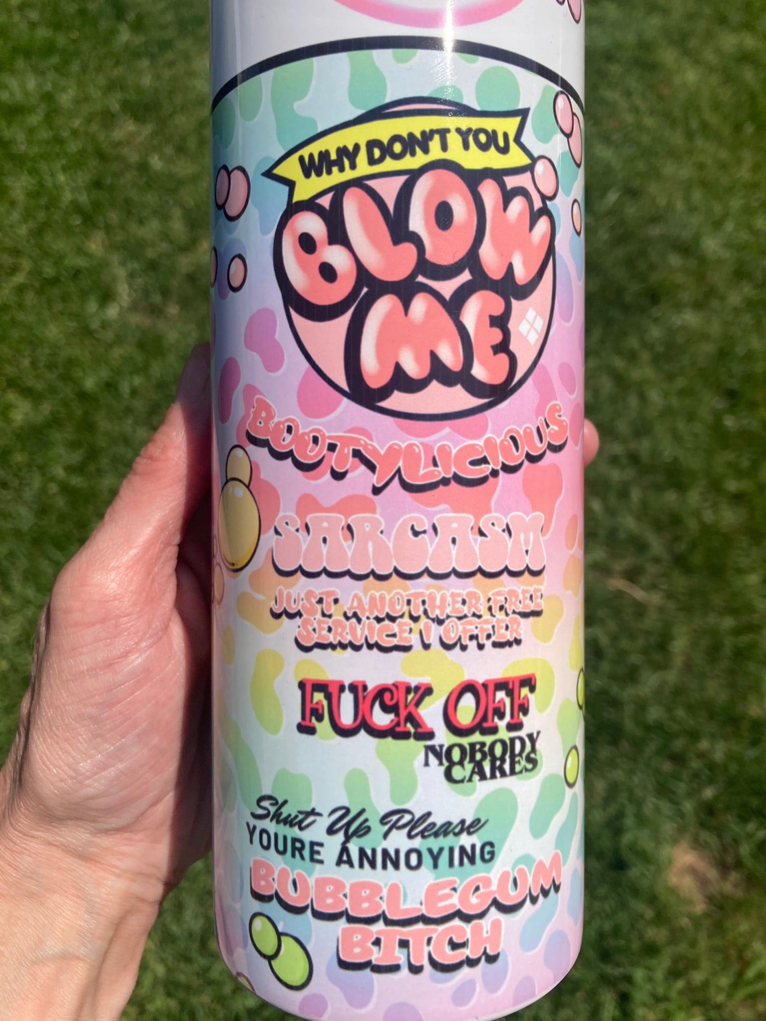 Cylindrical product with colorful text and graphics held against a grass background. 