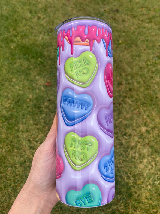 Tumbler with colorful heart-shaped conversation bubbles on a grassy background. Pastel candy heart tumbler with funny phrases like hell no, ewww, and just no