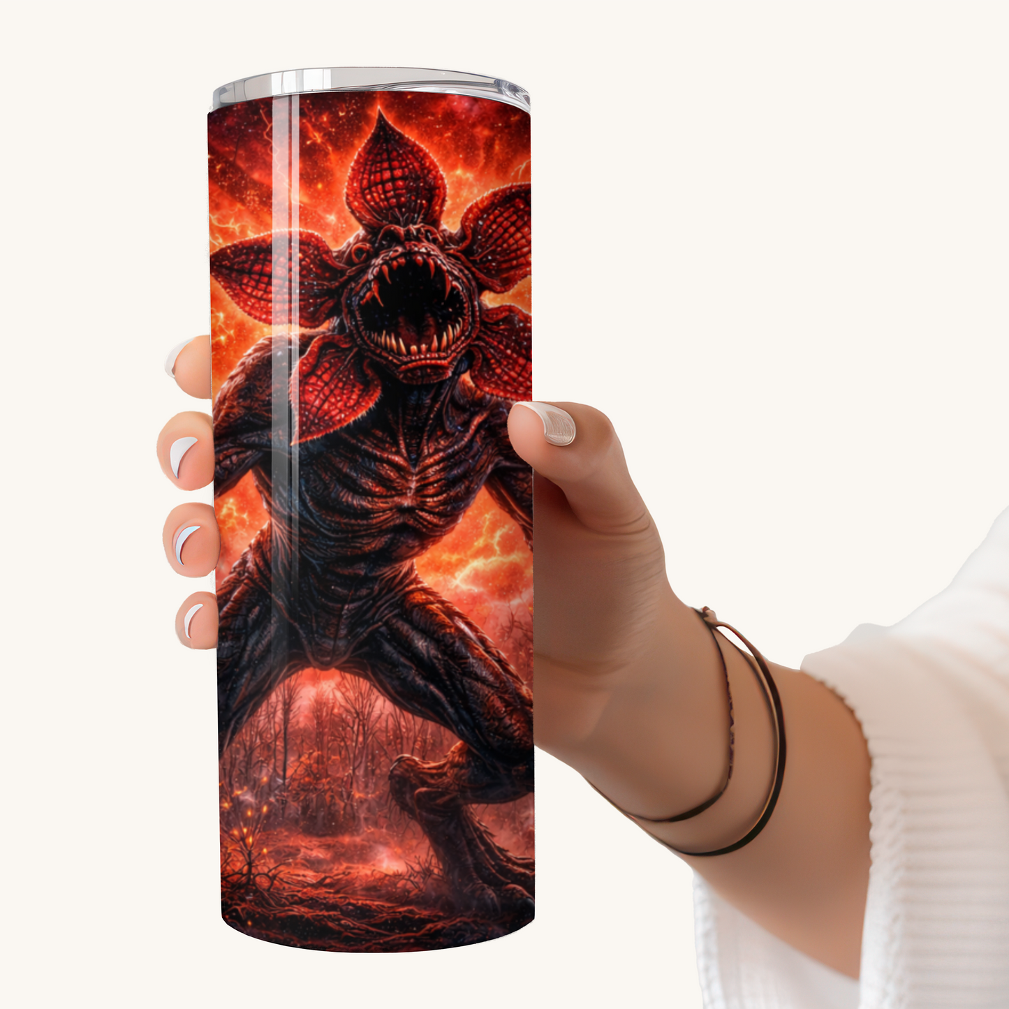 Hand holding a 20oz stainless steel tumbler featuring a Stranger Things–inspired Demogorgon creature design with fiery horror sci-fi artwork.