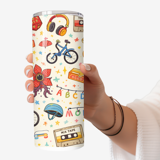 Hand holding a 20oz stainless steel tumbler featuring Stranger Things–inspired retro icons including bikes, cassette tapes, lights, and sci-fi imagery.