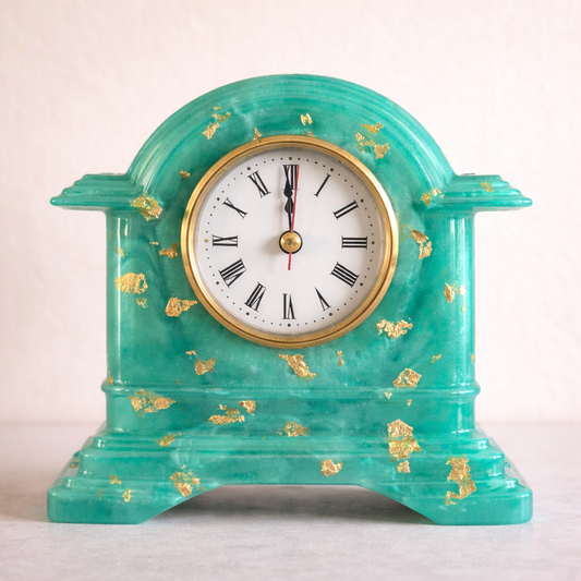 Turquoise clock with gold accents on a white background