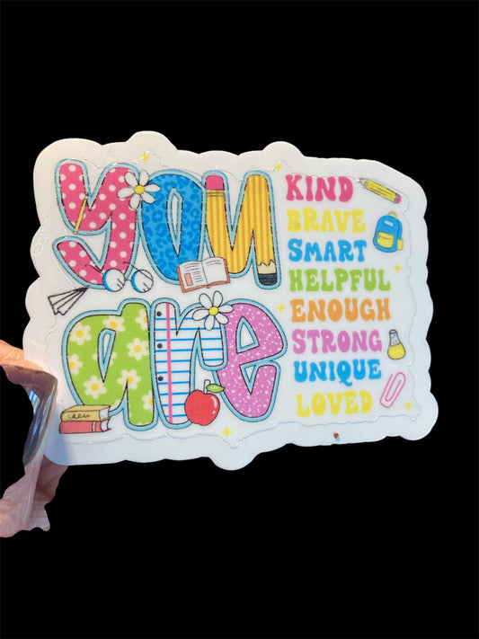 Colorful sign with motivational phrases held by a hand against a black background