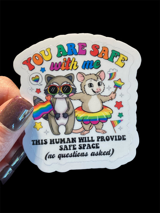 Sticker with cartoon animals and text about safe space, held by a hand.